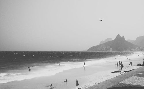 People at scenic beach against sky