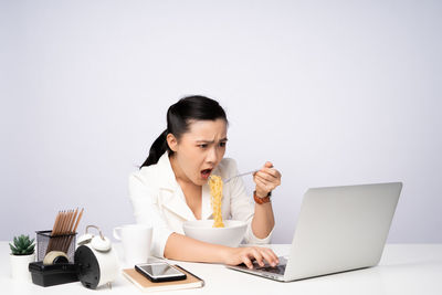 Young woman using mobile phone while sitting on table