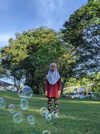 Full length of girl with arms raised playing with bubble