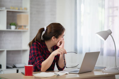 Woman using phone while sitting on table