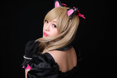 Woman in cosplay costume against black background