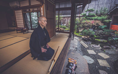 Man looking away while sitting outside building