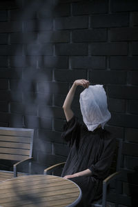 Rear view of woman wearing hat while sitting on table