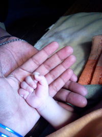 Close-up of father holding baby hand