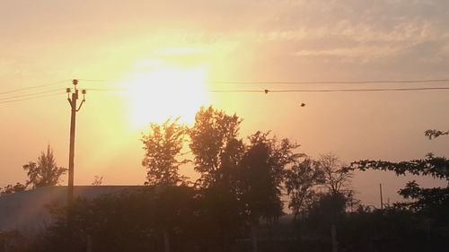 Low angle view of electricity pylon at sunset