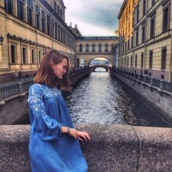 Young woman standing by canal in city