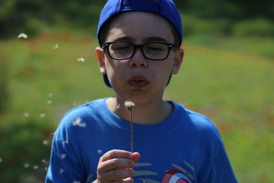 Close-up of boy blowing dandelion
