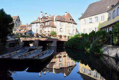 Buildings by canal against sky in city