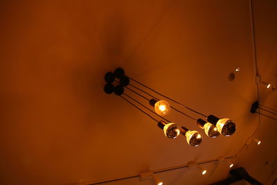 Low angle view of illuminated light bulb against sky during sunset