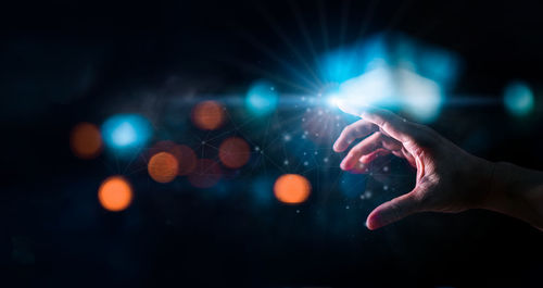 Cropped hand of person holding illuminated lights at night