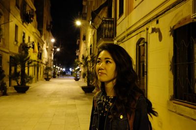 Portrait of woman standing on street in city at night