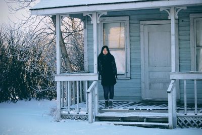 Portrait of woman standing at house entrance during winter