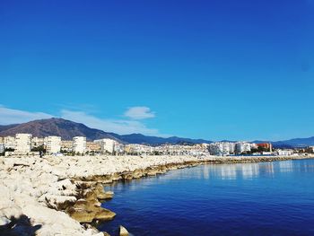 Scenic view of sea and mountains against clear blue sky