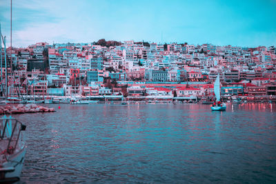 Sailboats in sea against buildings in city