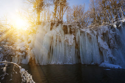 Frozen waterfall against sky during winter