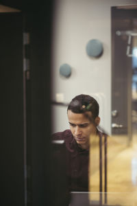 Businessman working at desk seen through glass in office