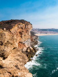 Rock formations by sea against blue sky