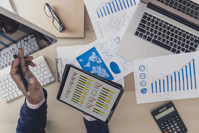 Cropped hand of businessman holding digital tablet at office