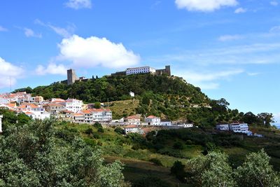 Panoramic view of buildings and trees with a castle on the top against sky
