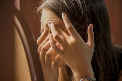 Close-up of young woman applying make-up