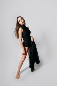 Studio portrait of young woman with long hair. fashionable stylish girl in black bodysuit on grey