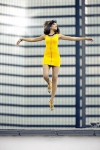 Full length of woman levitating against building