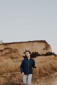 Full length of man standing on field against clear sky