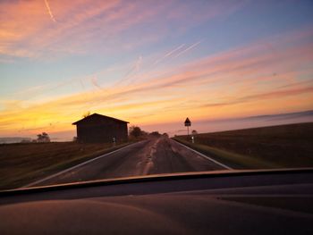 Road against sky during sunset seen through car windshield