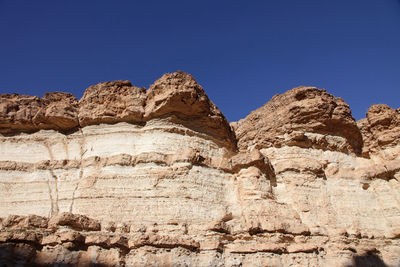 Low angle view of rock formation against clear blue sky at sahara desert