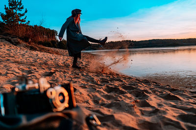 Full length of woman on beach against sky during sunset