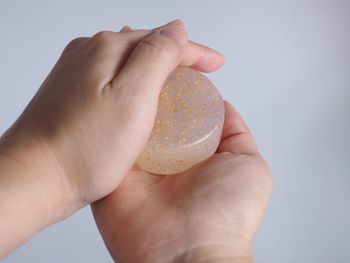 Close-up of person holding soap in hands over white background