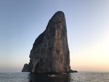 Rock formation in sea against clear sky