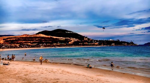 People on beach by sea against sky