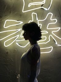 Rear view of woman standing on illuminated wall