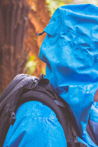 Side view of backpack person wearing raincoat during rainy season