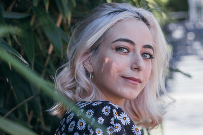 Portrait of beautiful young woman against tree