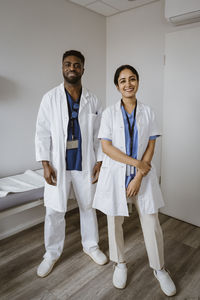 Smiling male and female medical colleagues standing in consulting room