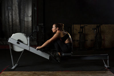 Side view of determined muscular female athlete doing seated cable row exercise during functional workout in modern gym