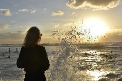 Rear view of woman looking at sea during sunset