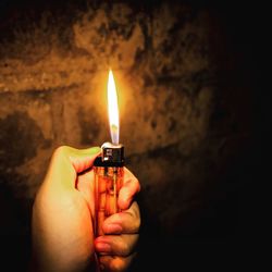 Cropped hand of person igniting cigarette lighter in darkroom