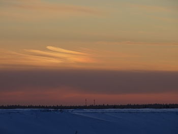 Scenic view of snow covered field against sky during sunset