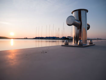 Scenic view of sea against sky during sunset focus on a bollard