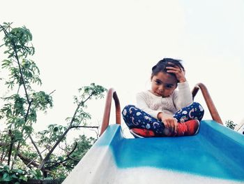 Portrait of boy sitting on plant against sky