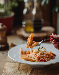 Cropped hand of woman eating food at restaurant