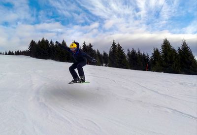 Full length of man skateboarding on snowy mountain against sky