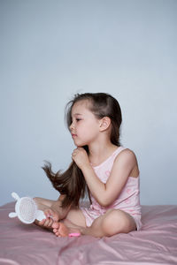 Portrait of smiling girl sitting on bed at home