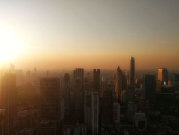 Aerial view of buildings in city against sky during sunset