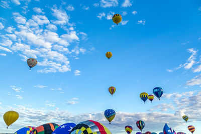 Low angle view of hot air balloons flying against blue sky