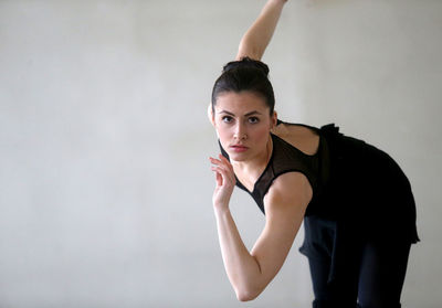 Portrait of young woman doing ballet dance against white background
