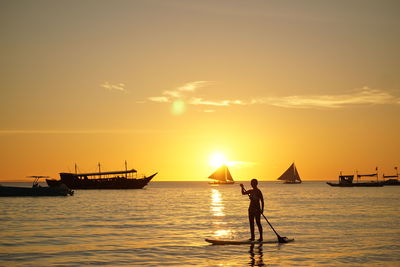 Silhouette man on sea against sky during sunset